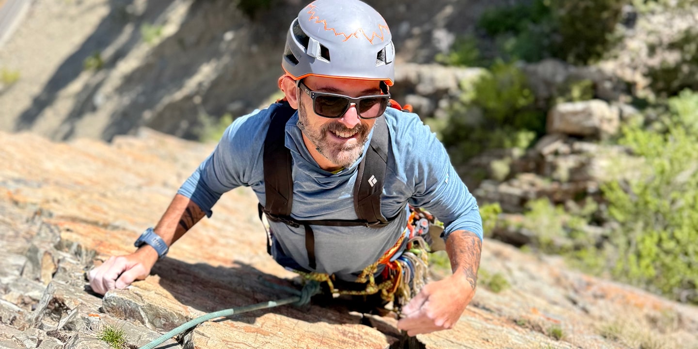A man in a grey helmet rock climbing