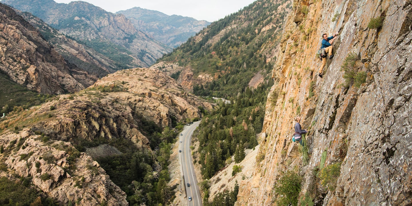 People rock climbing with a road below