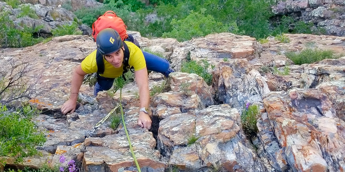 A man in a yellow shirt rock climbing