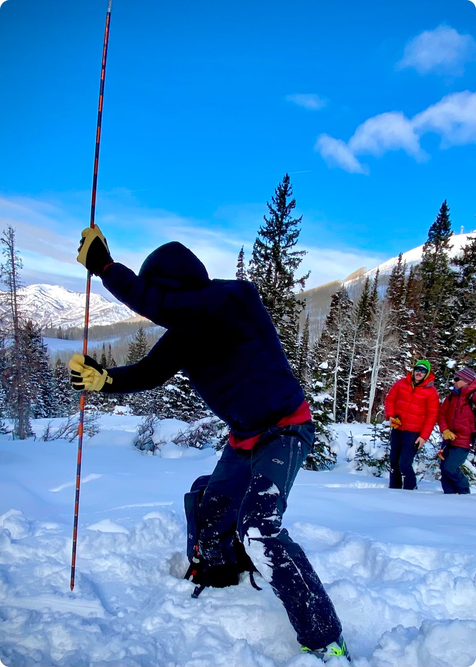 A person stabs a probe into the ground during an avalanche training course