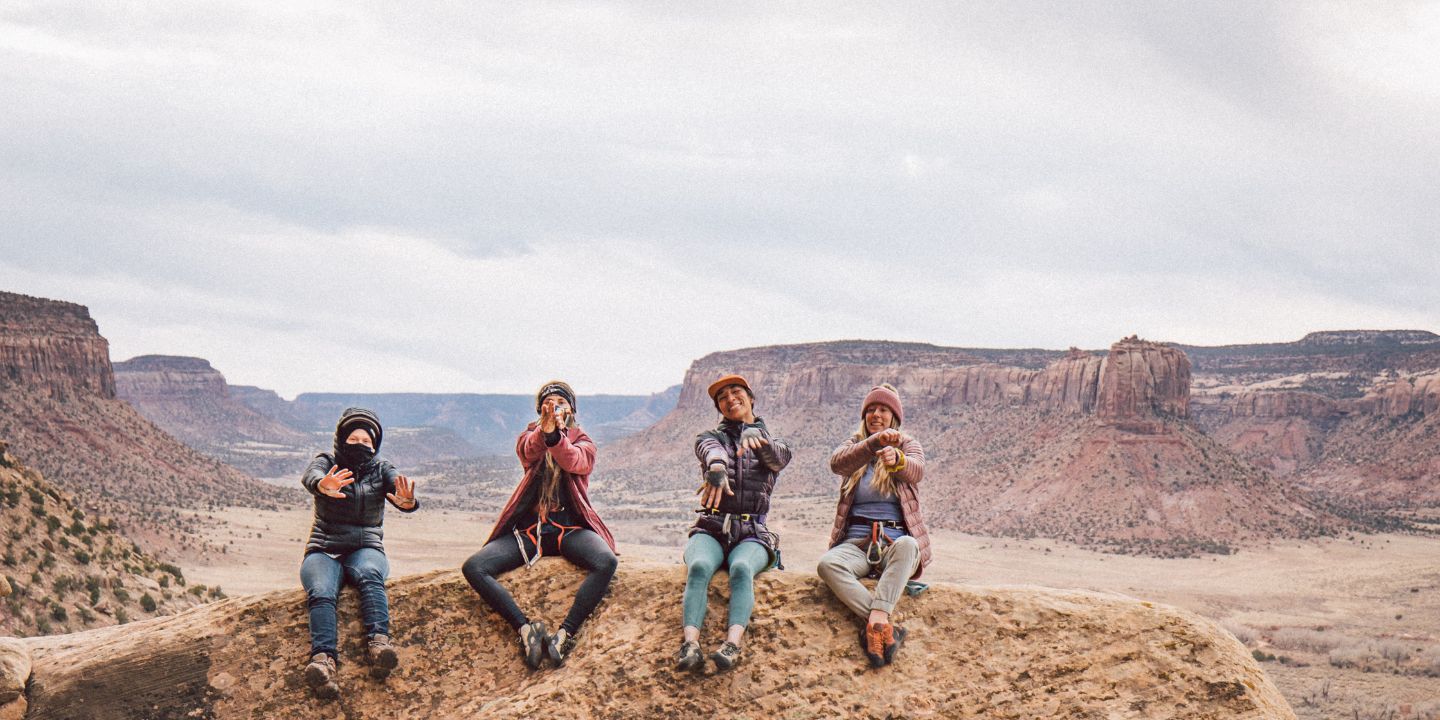 Four people sit at the top of a rock formation while rock climbing