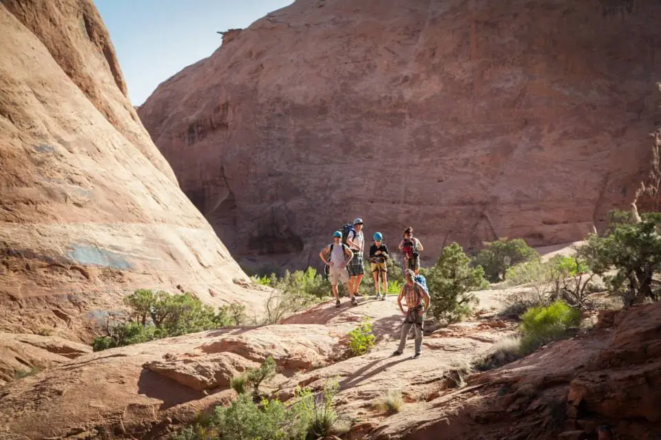 Five people in a canyon stand with helmets and climbing gear