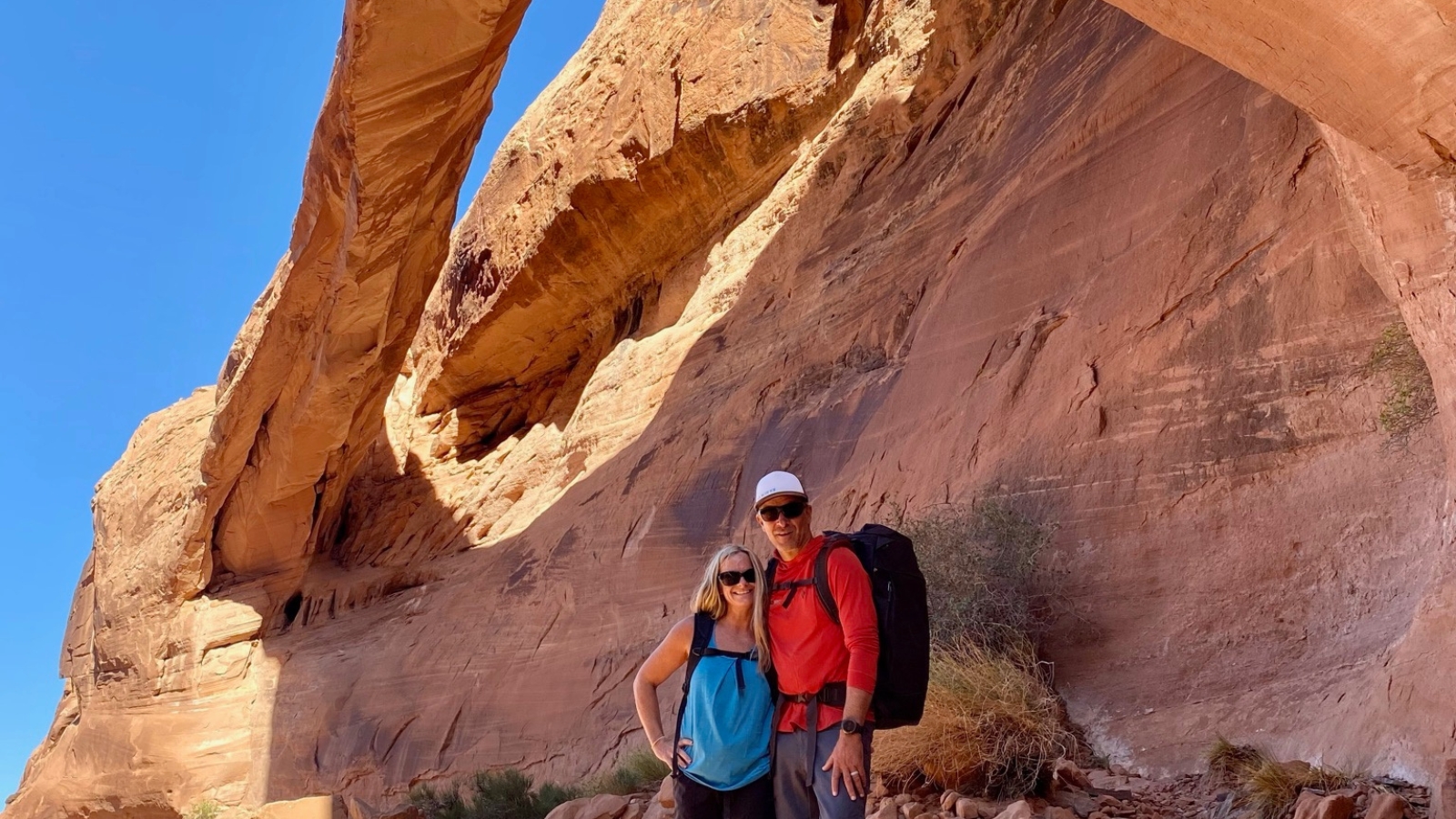 a couple poses in front of an arch while hiking in moab