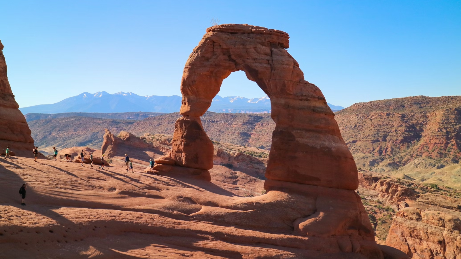 hikers stand under moab's delicate arch
