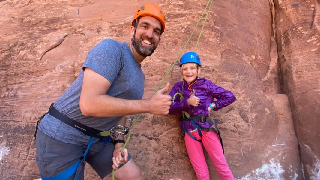 a man and child in climbing gear smile for a photo