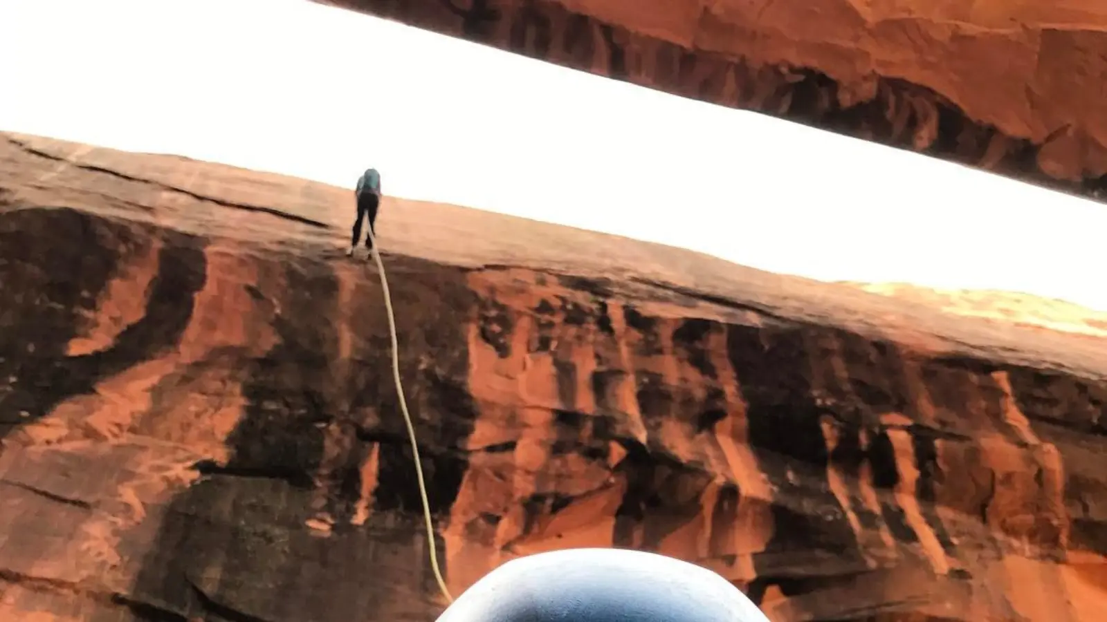A person rappels down a large rock formation in Moab