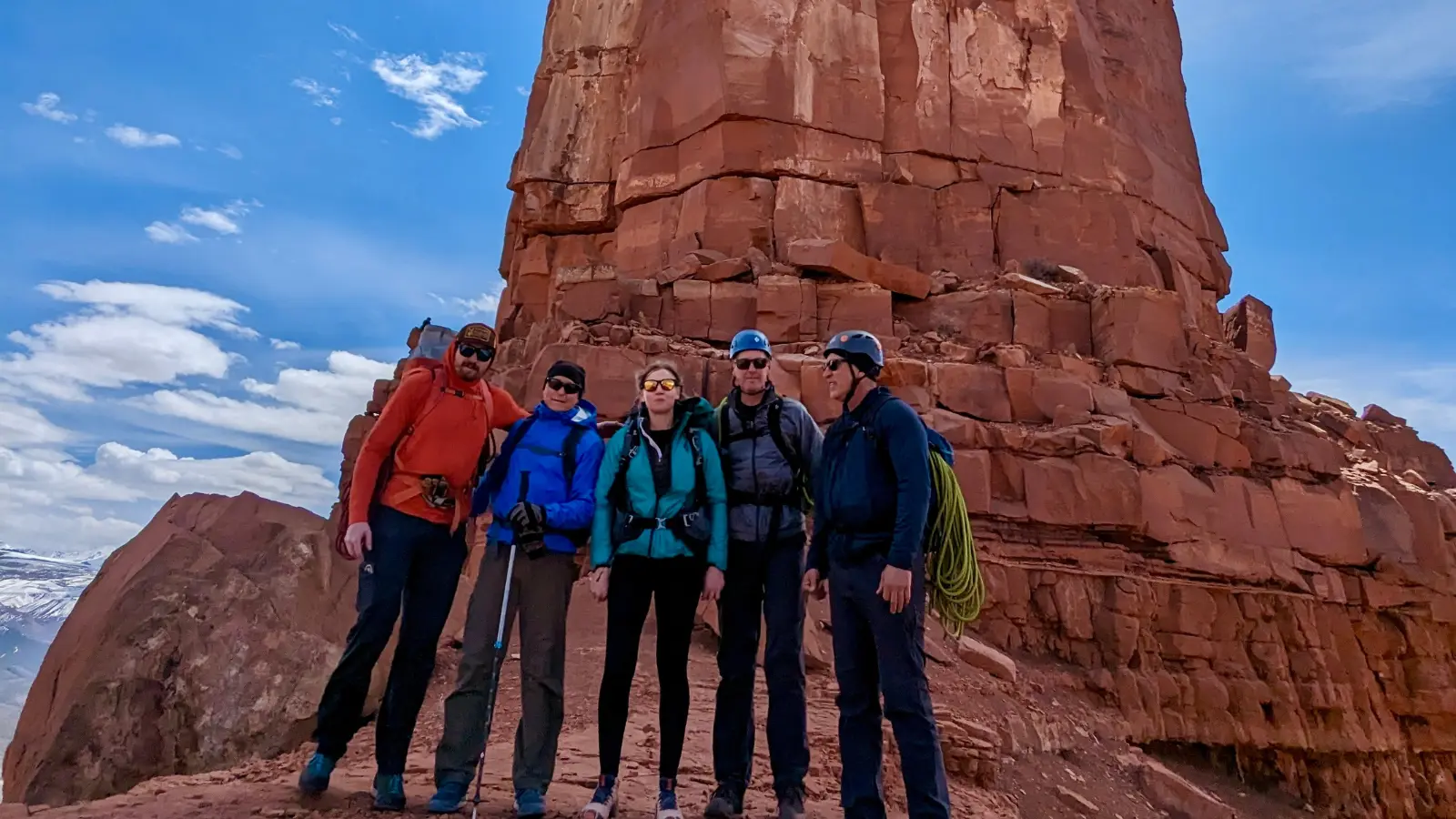 five people pose in front of a rock feature in moab