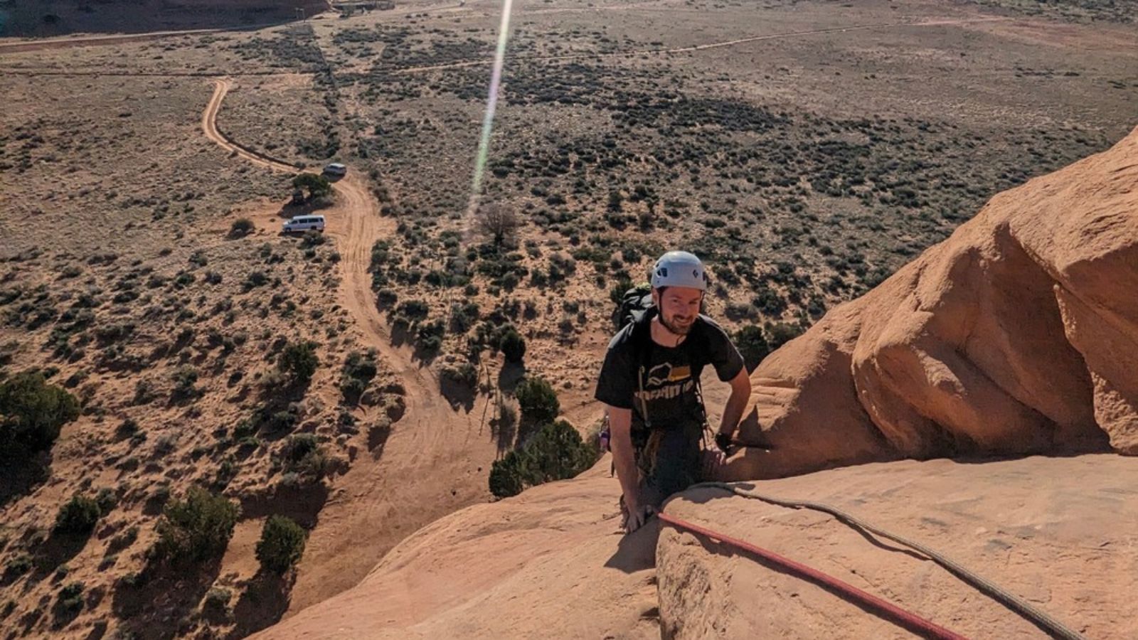 person climbing looking glass arch in Moab