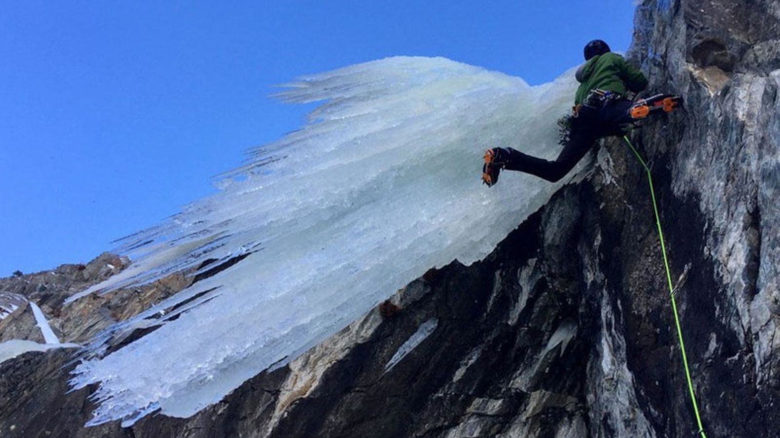 A man ice climbing next to a frozen sheet of ice