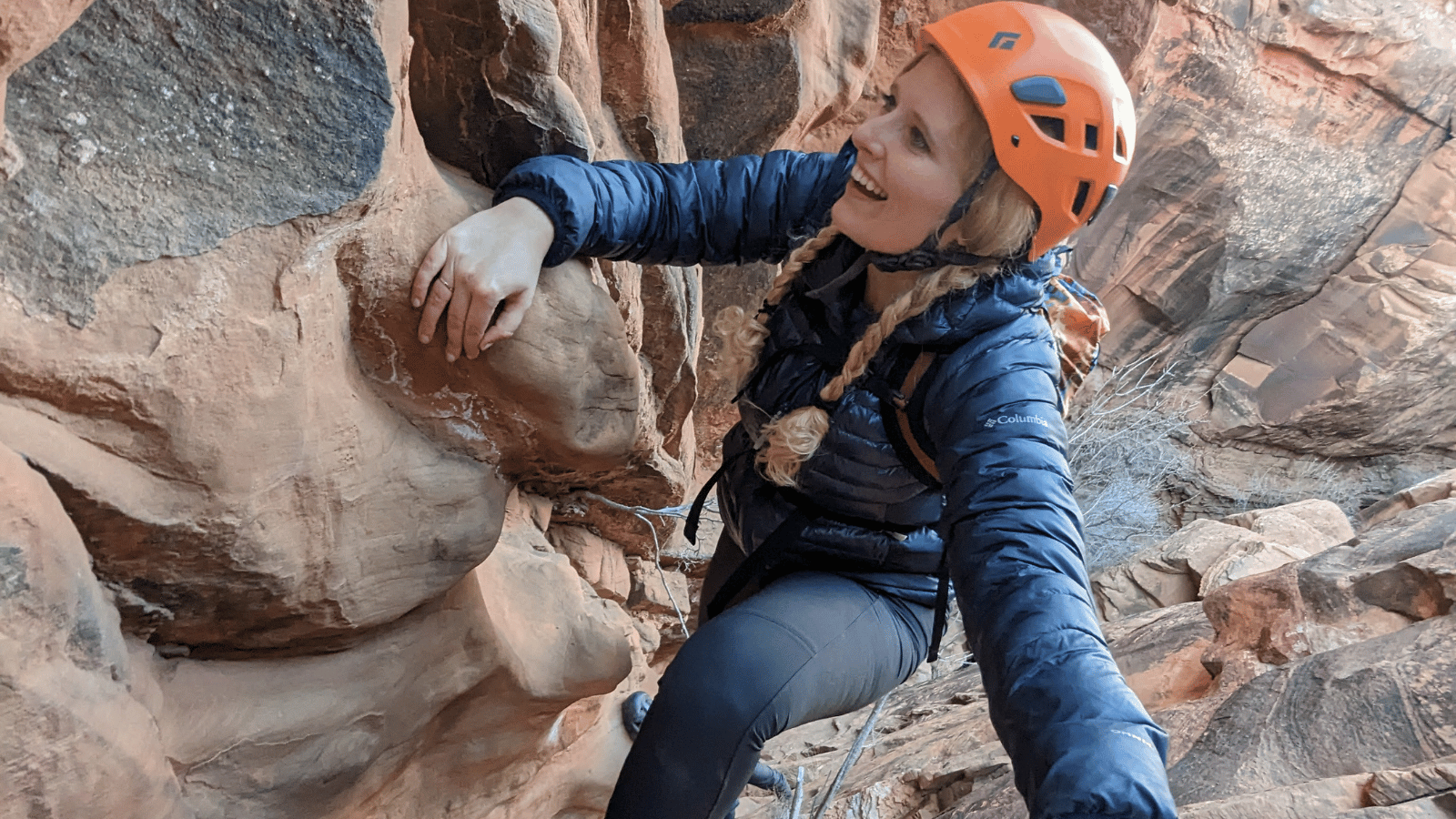 a woman scrambles up rock on a moab hike